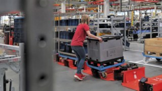 O operador carrega um reboque de comboio logístico com um trolley de tamanho reduzido