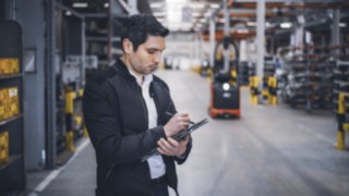 Um colaborador da Linde Material Handling no armazém a tomar notas no seu tablet.