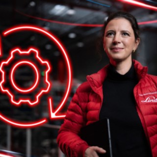 Colaboradora da Linde Material Handling num armazém, com um símbolo vermelho luminoso de uma roda dentada em segundo plano.