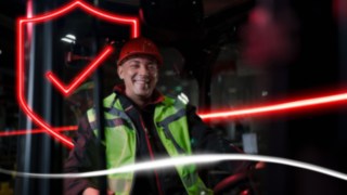 Pessoa com vestuário de trabalho e capacete de proteção sentada num empilhador da Linde