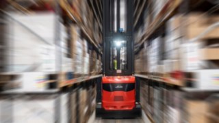 Um empilhador para corredores estreitos da Linde Material Handling em operação num pavilhão de armazenamento.