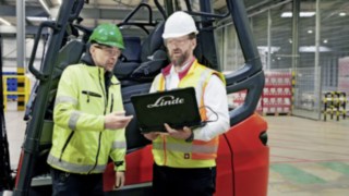 Há sete anos que o Linde Safety Guard presta um serviço fiável nas duas instalações da Heineken. Dois colaboradores com um computador portátil em frente a um empilhador da Linde MH