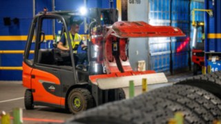 Um colaborador da Michelin Tyre PLC utiliza uma pinça para pneus no Linde E20 para agarrar uma pilha de pneus.