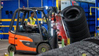 Um colaborador da Michelin Tyre PLC agarra uma pilha de pneus com uma pinça montada no empilhador.