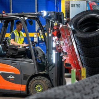 Um colaborador da Michelin Tyre PLC agarra uma pilha de pneus com uma pinça montada no empilhador.