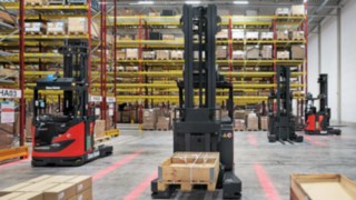 Os R-MATIC da Linde MH esperam em frente à estanteria pela próxima tarefa de transporte