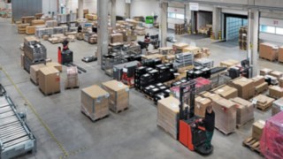 Armazém de logística da Simon Hegele com colaboradores a selecionar e transportar paletes com mercadorias.
