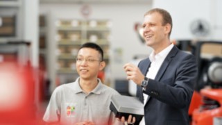 Colaborador da Linde com um colega do estrangeiro no pavilhão da fábrica Colaborador da Linde com um colega do estrangeiro no pavilhão da fábrica