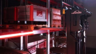 Um empilhador retrátil da Linde do tipo Ri16 transporta paletes numa área de estanterias.