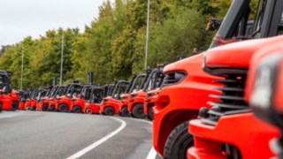 Muitos empilhadores da Linde Material Handling alinhados num parque de estacionamento.